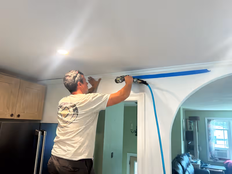 Empirical Renovations carpenter nailing crown molding above a kitchen doorway in Vermont