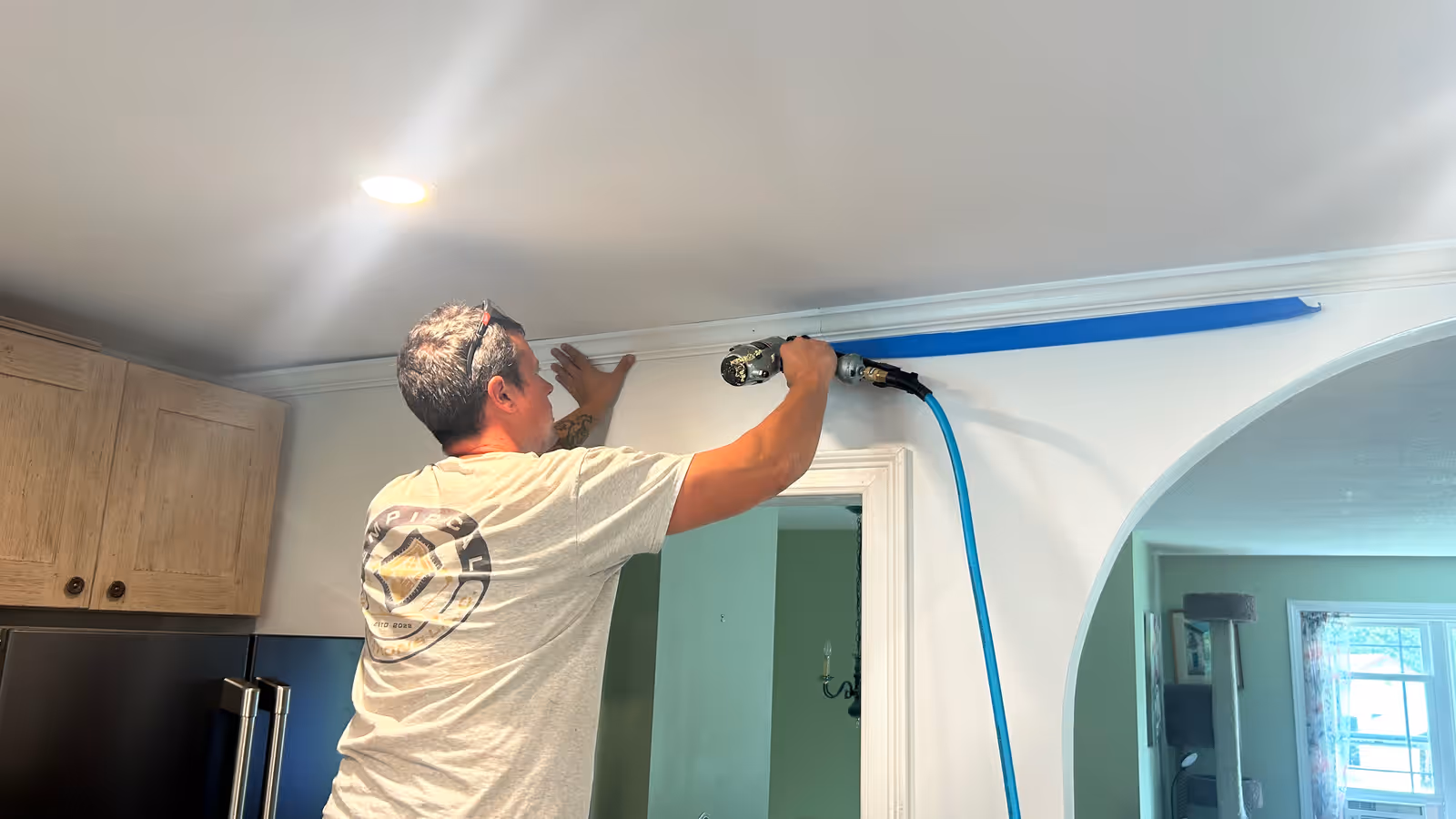 Empirical Renovations carpenter nailing crown molding above a kitchen doorway in Vermont