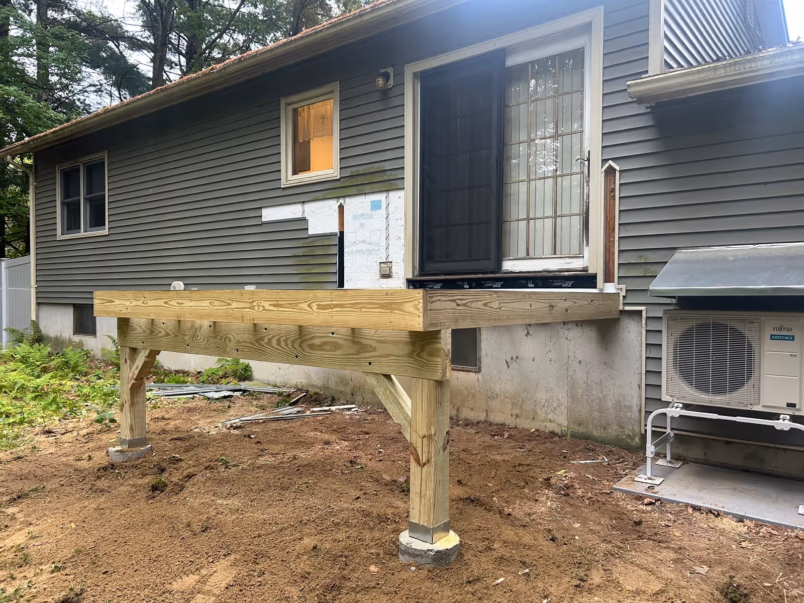 Pressure-treated beam, posts and concrete footings framed off the back of a house in Milton VT, before decking went down