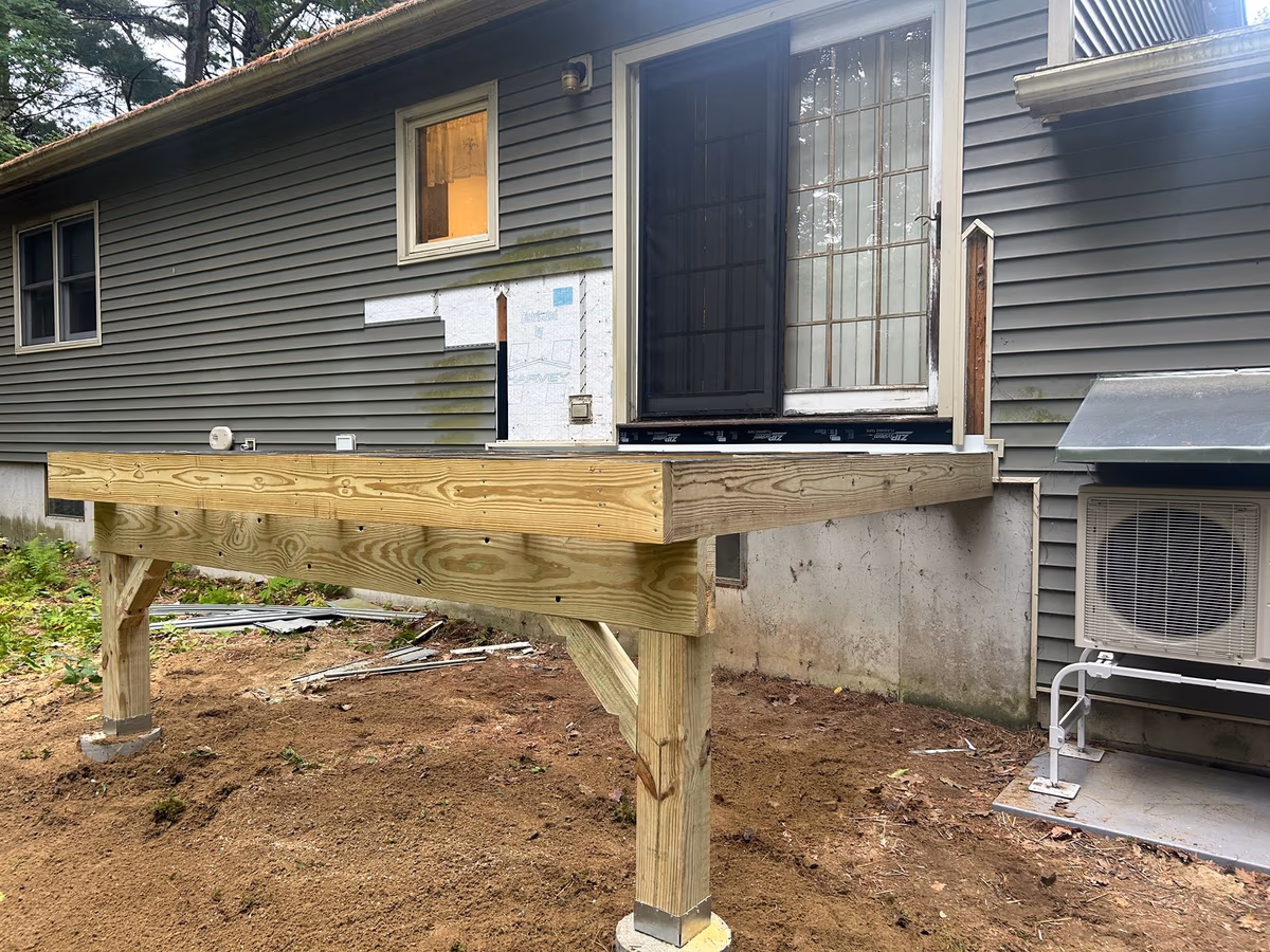 Pressure-treated posts on concrete footings carrying the deck beam in Milton VT