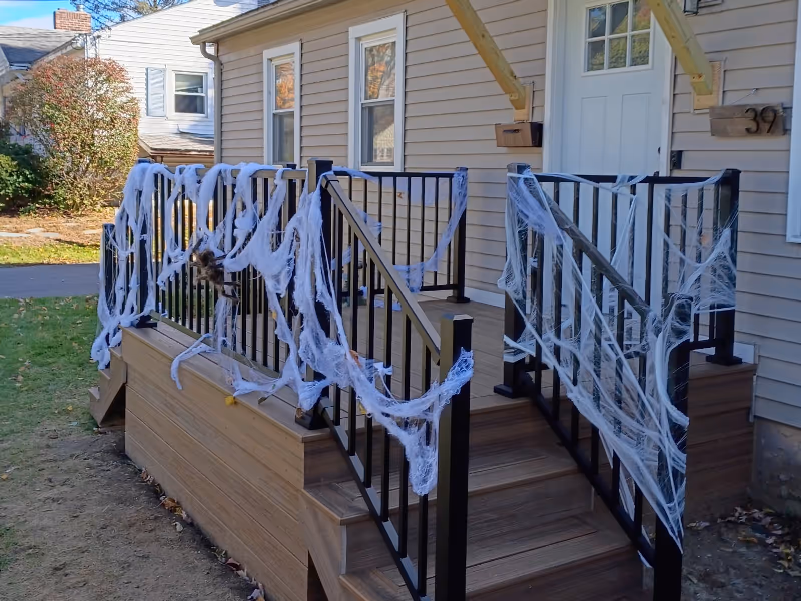 The same front deck rebuilt by Empirical Renovations in Havana Gold Trex with black Trex Select railings and two sets of stairs