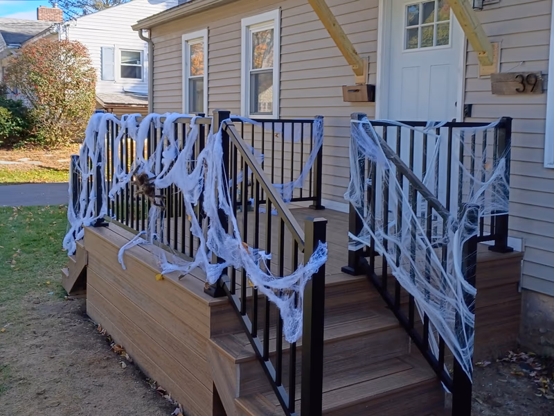 Havana Gold Trex front deck with black aluminum railings and stairs, built by Empirical Renovations in South Burlington VT