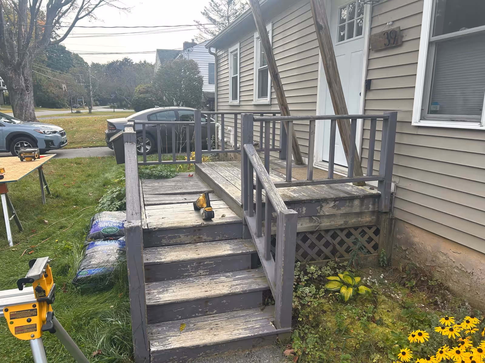 The original 1970s front deck in South Burlington VT, boards weathered gray and rotted through in places, before it was torn out