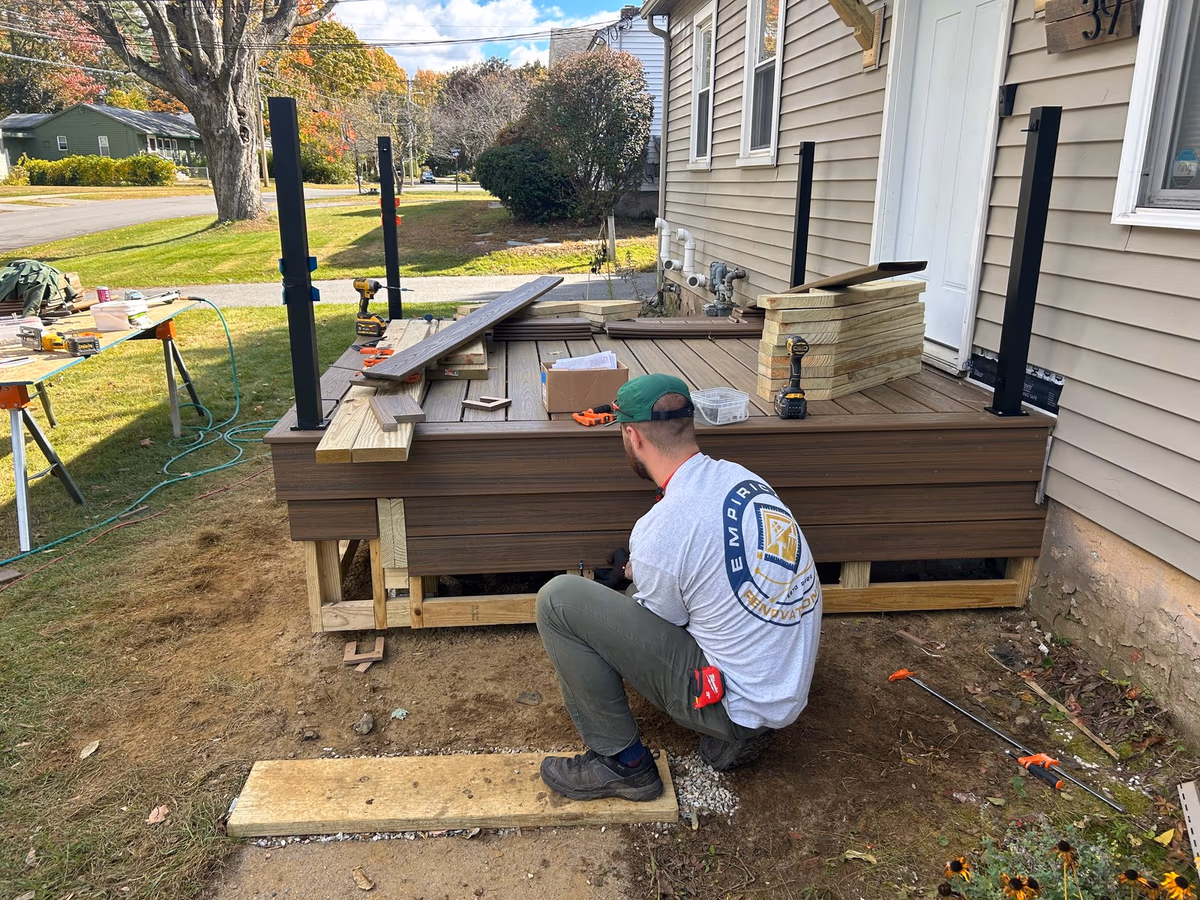 Empirical Renovations crew member fastening Havana Gold Trex deck boards to the new frame