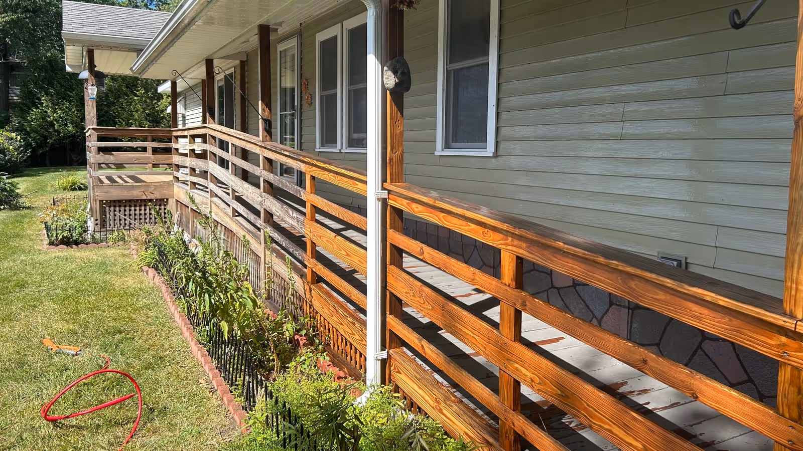 Porch railing half pressure washed by Empirical Renovations, clean bright wood on one side and weathered gray on the other