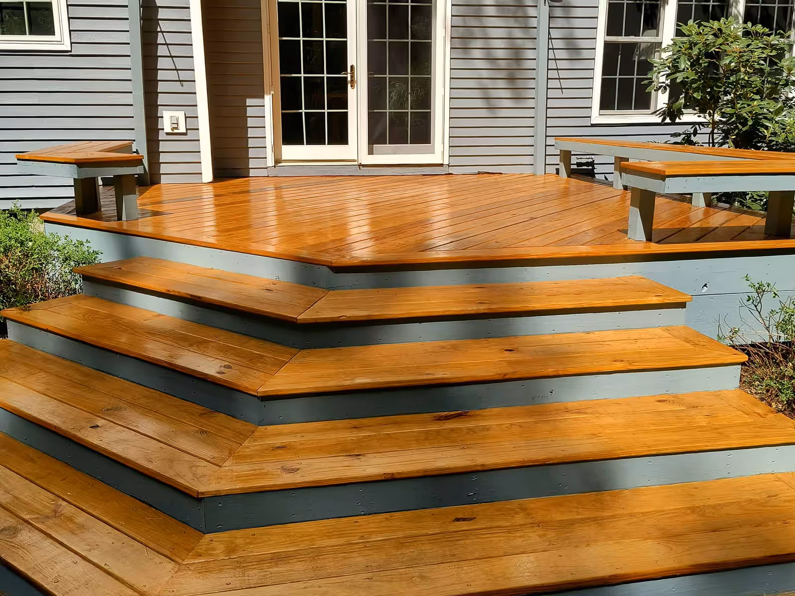 The same deck and wraparound steps after staining by Empirical Renovations, finished in a warm amber semi-transparent stain