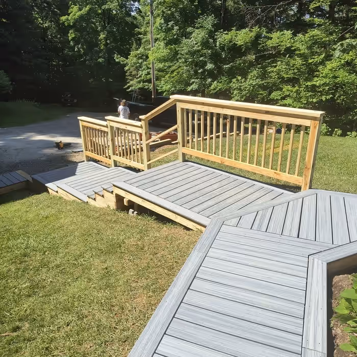 The same walkway rebuilt by Empirical Renovations in gray composite decking, with a new landing, steps and pressure-treated railings