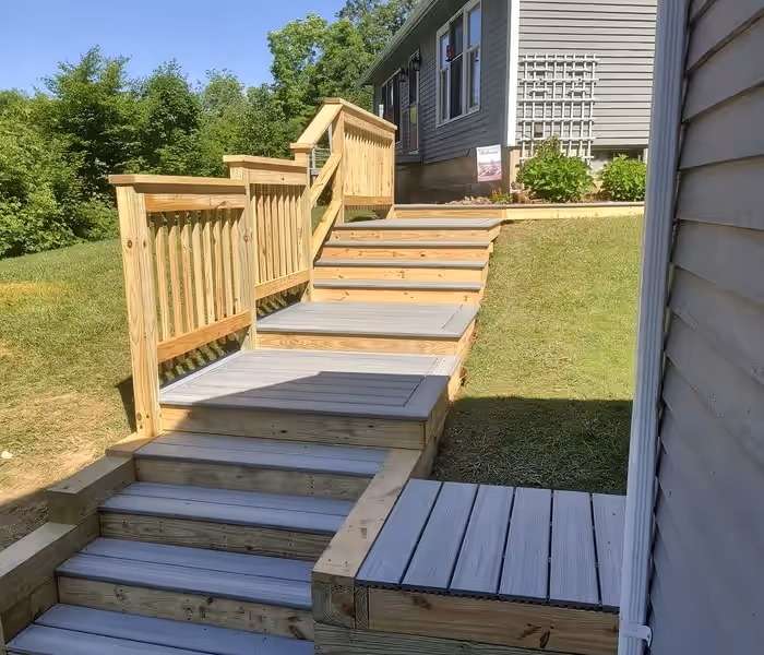 Composite deck walkway with pressure-treated stairs and railings connecting a Vermont home to the yard, built by Empirical Renovations