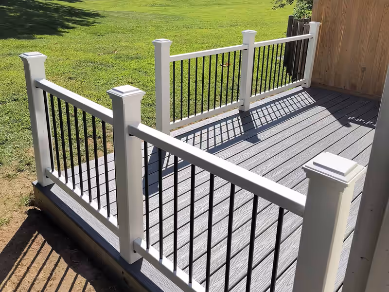 Low freestanding deck in gray composite with white railing and black balusters, built by Empirical Renovations in Vermont