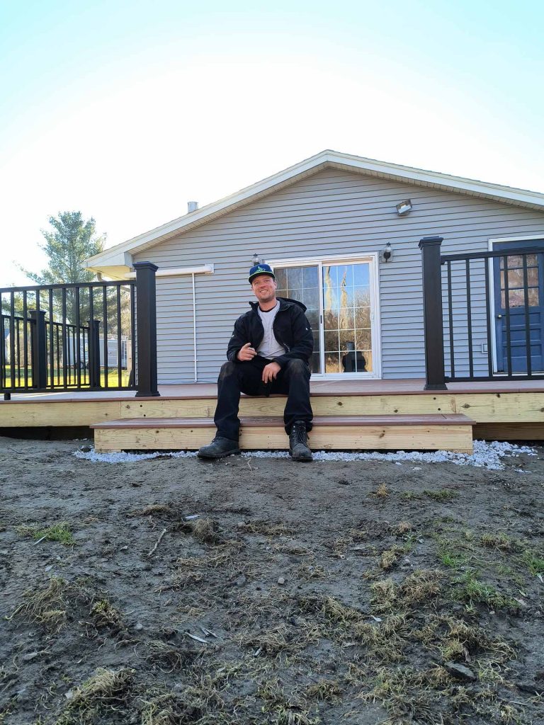 Worker from Empirical Renovations LLC logo poses on newly built deck