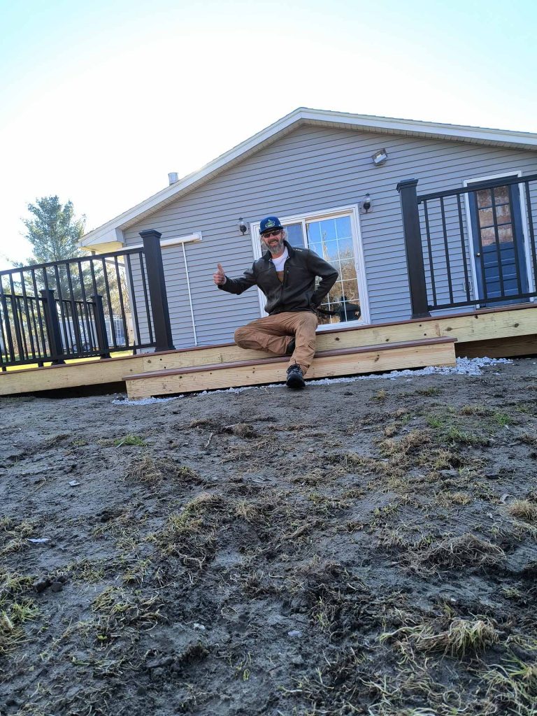 Worker from Empirical Renovations LLC logo poses on newly built deck