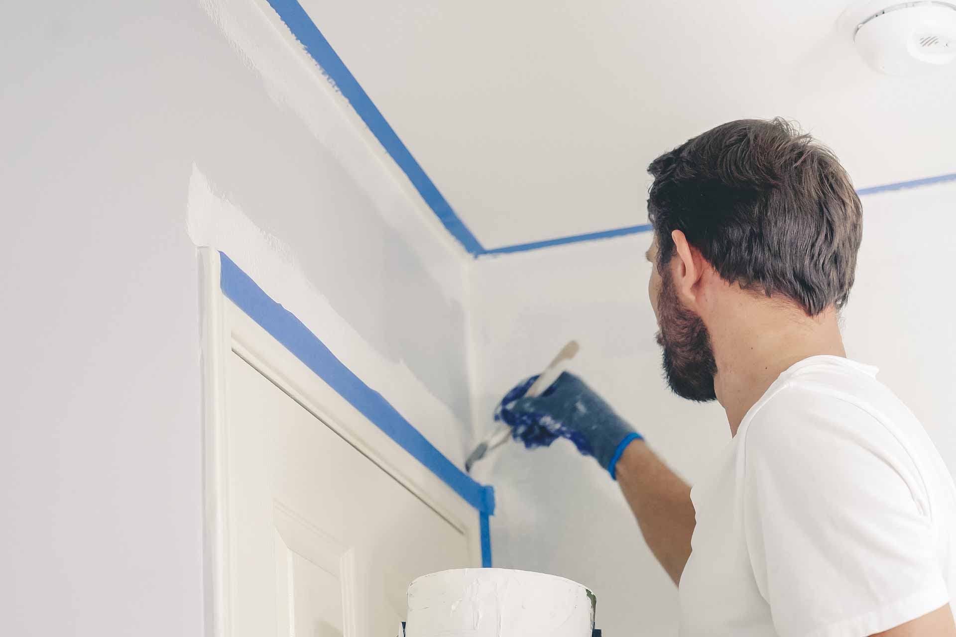 Man paints around interior door frame