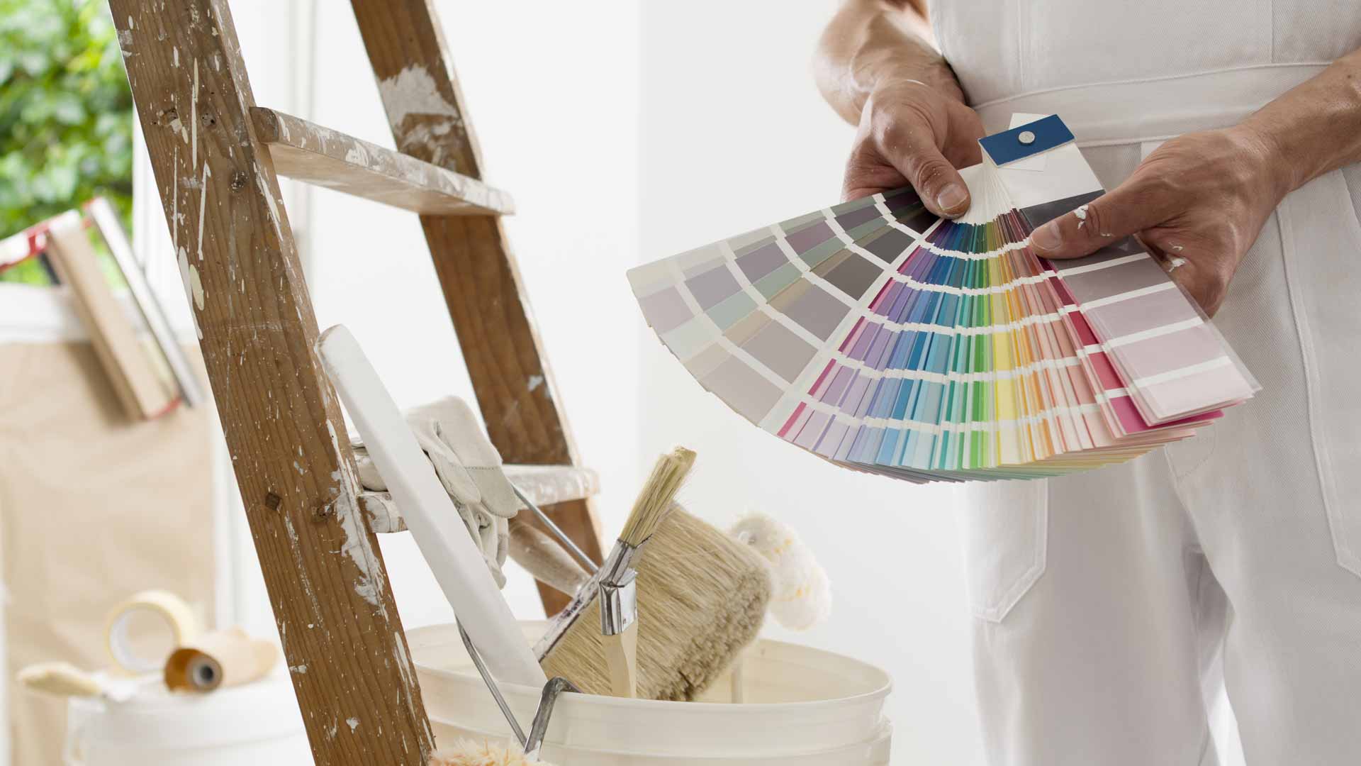 Man in white painters holding out book of color swatches